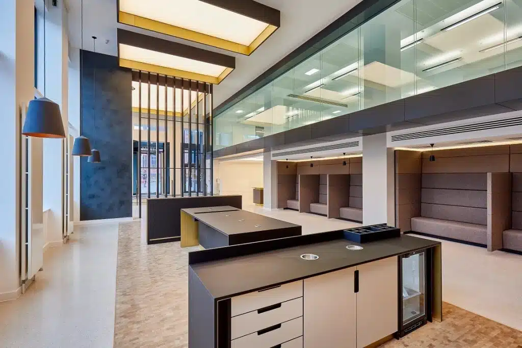 large open plan office entrance hall with stone floors, large feature lighting and brown seating booths.