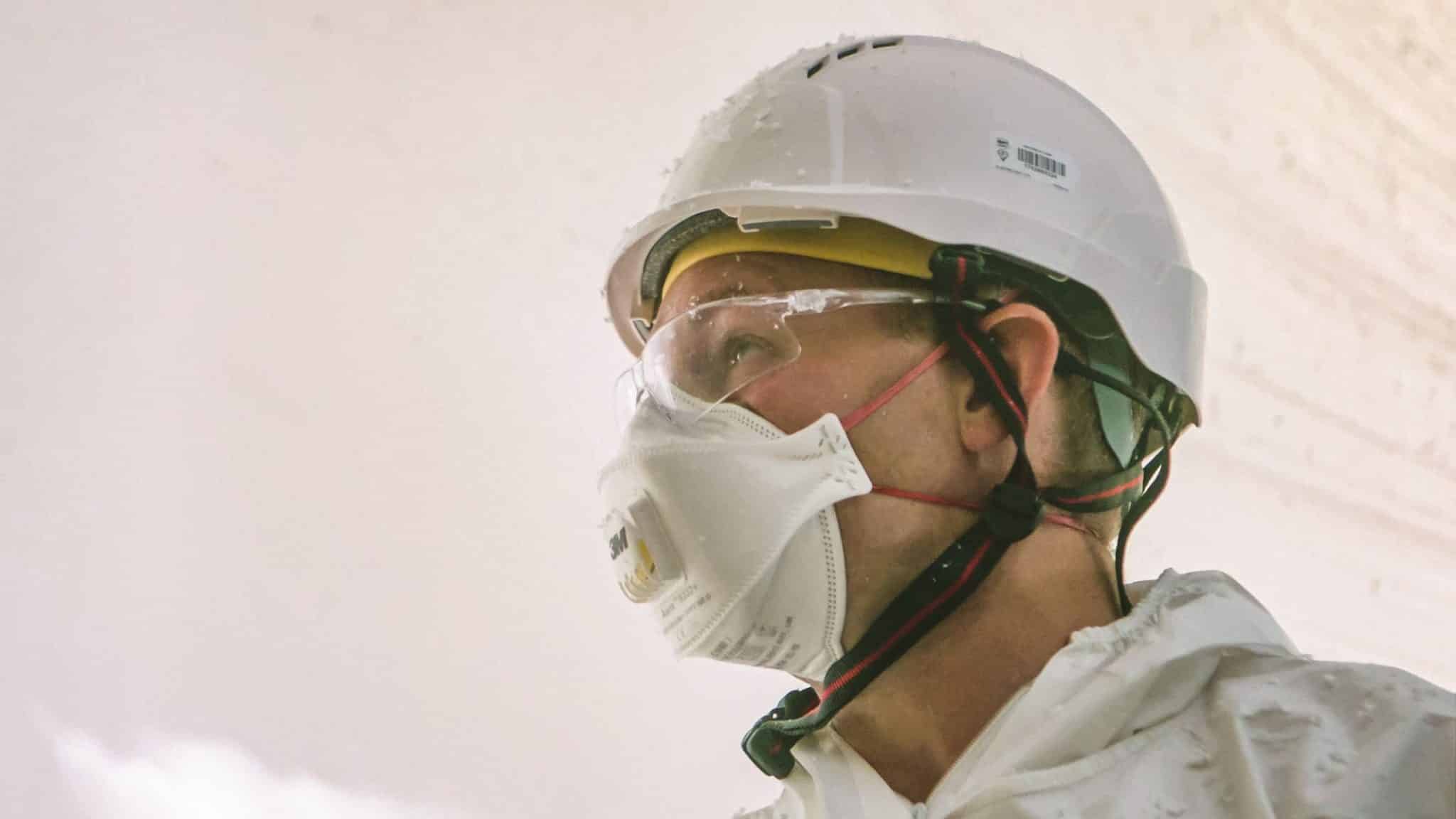 Oscar Acoustics' Ben C equipped in safety googles, mask and Helmet for acoustic spraying.