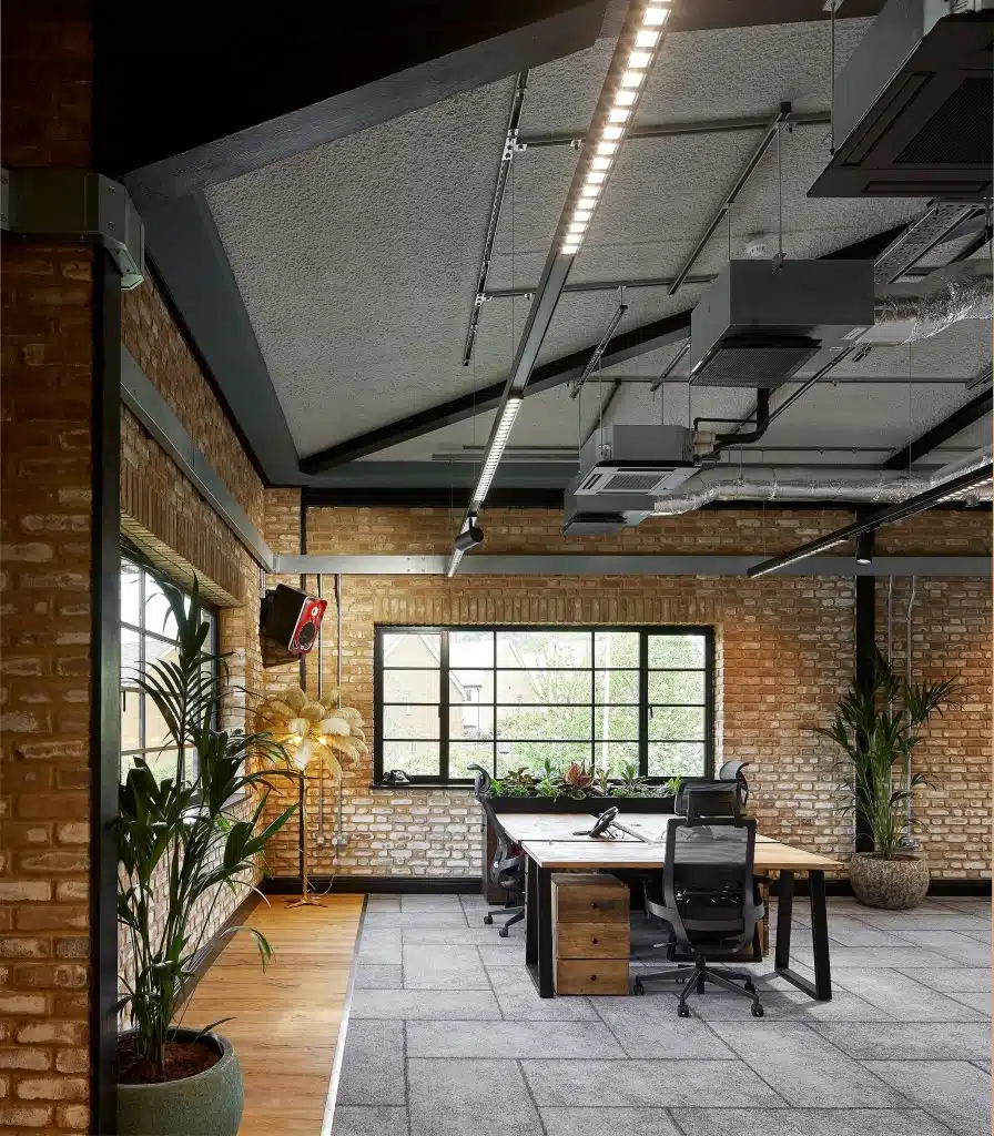 Modern office with brick walls, plants and SonaSpray K-13 Special, acoustic spray applied to the ceiling in light grey.
