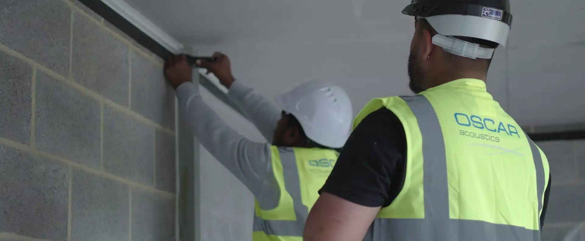 Oscar Acoustics' sprayers working in on a site. White Safety Helmets and Yellow high vis jackets.